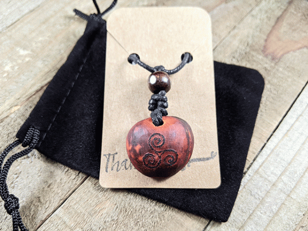 hand-carved avocado stone necklace with burned triskelion pattern