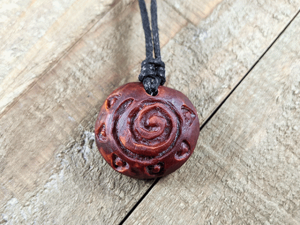 hand-carved avocado stone necklace with sun spiral
