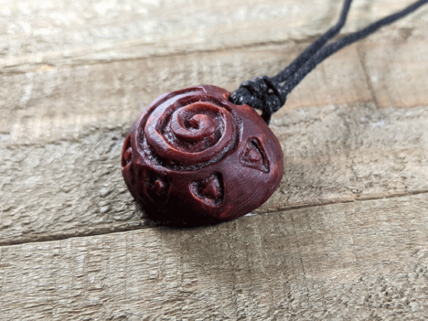 hand-carved avocado stone necklace with sun spiral