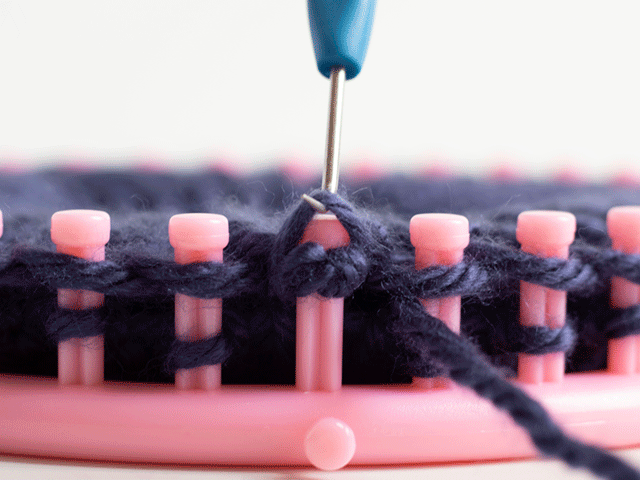 how to loom knit a tiny hearts beanie - lift yarn up and over the peg