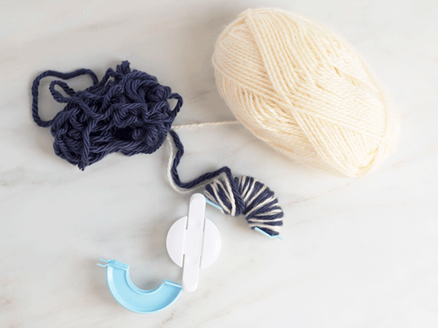 how to loom knit a tiny hearts beanie - wrap yarn around pom pom maker